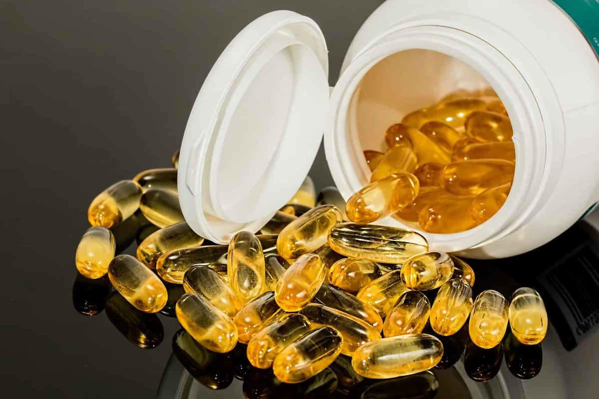 Capsules molles dorées qui débordent d’un flacon blanc