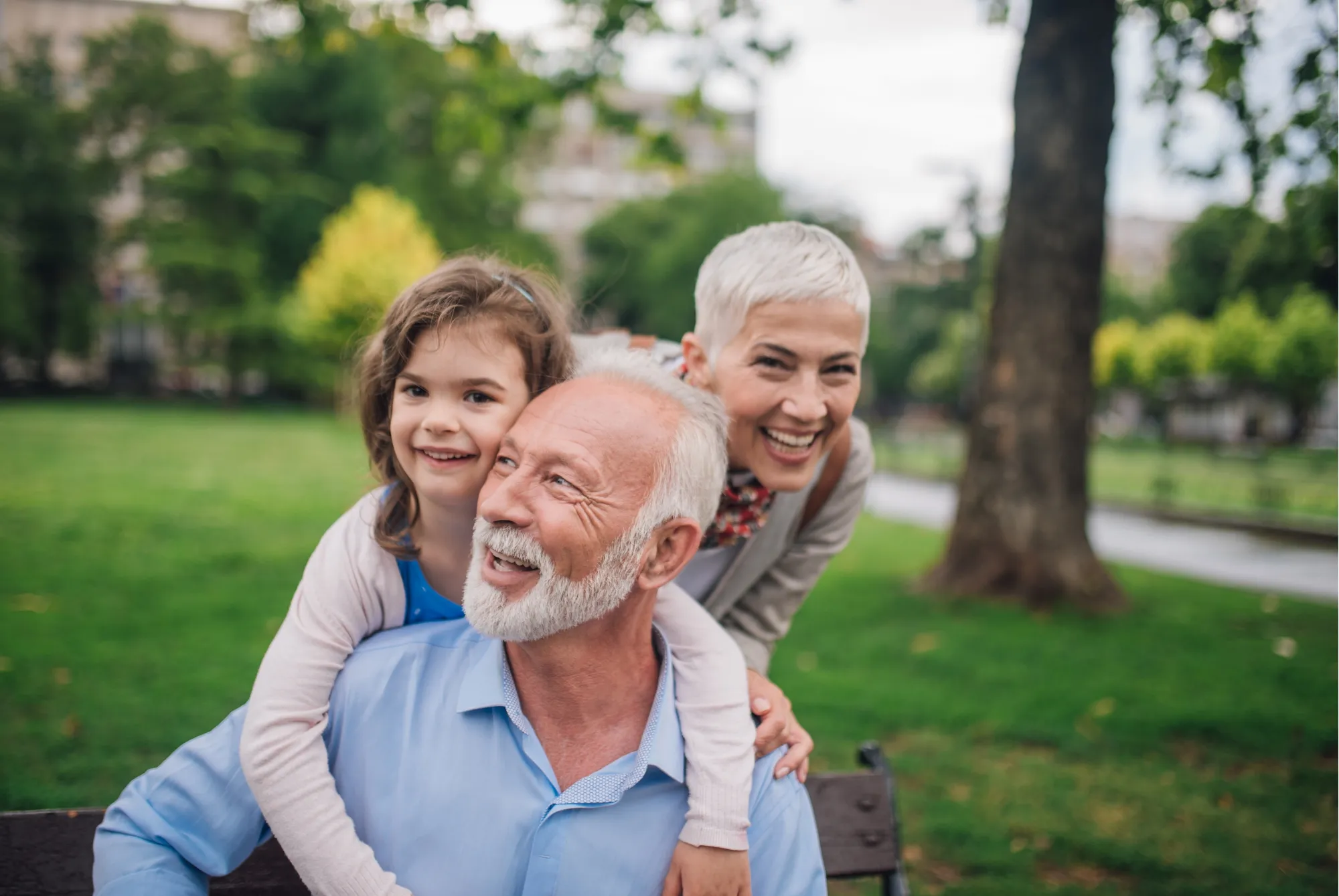 Grandparents and their granddaughter laughing in a park