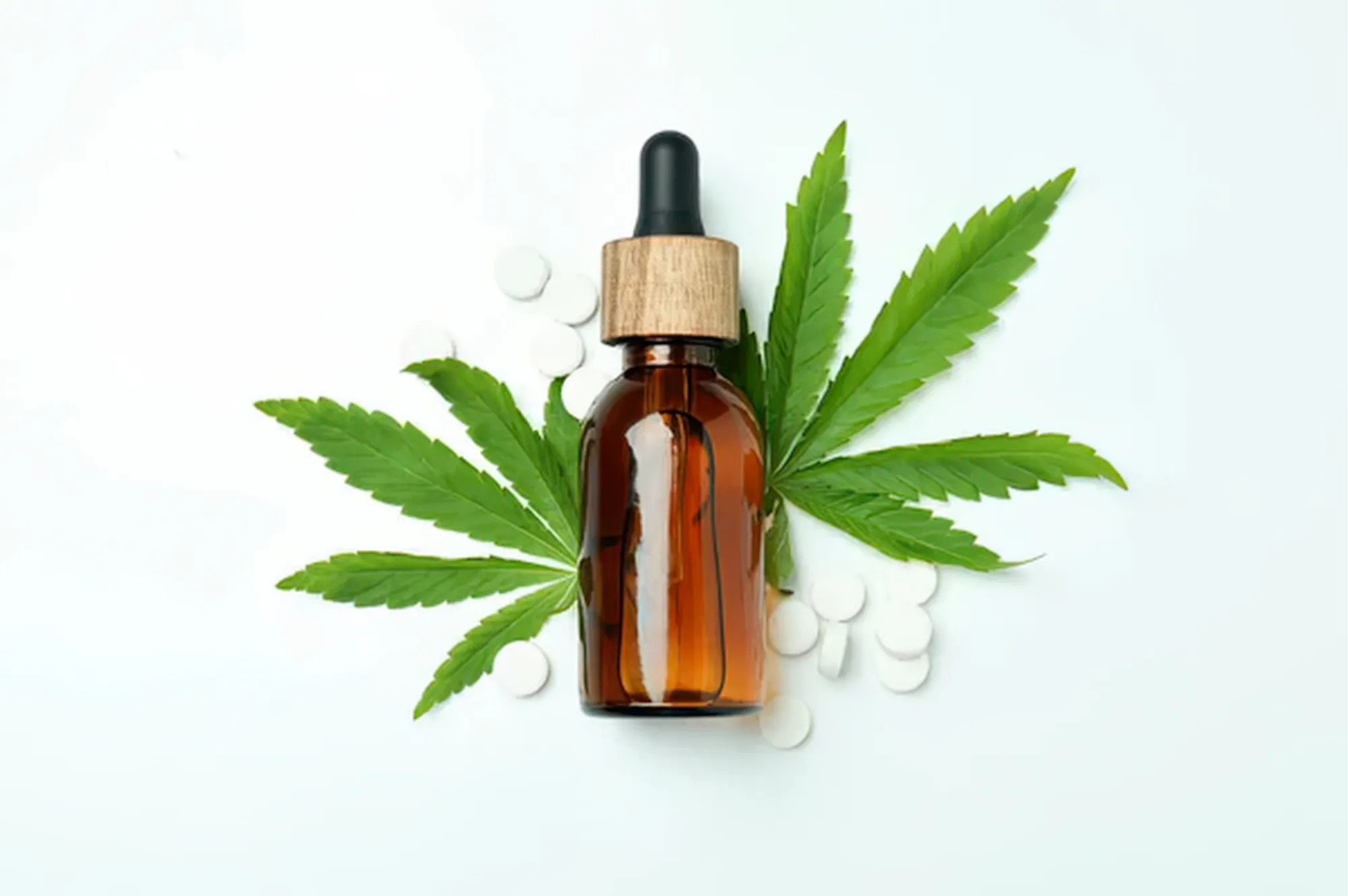 Flacon d’huile de CBD entre deux feuilles de cannabis