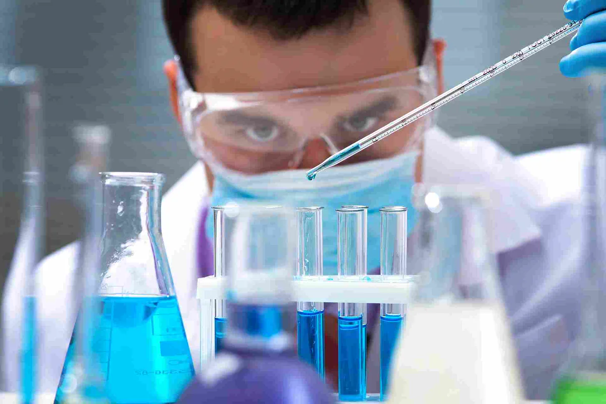 Masked technician pipetting samples into tubes