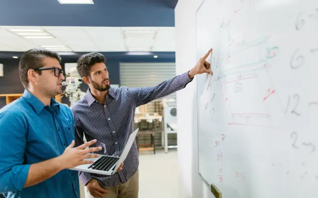 Deux ingénieurs définissent les besoins au tableau