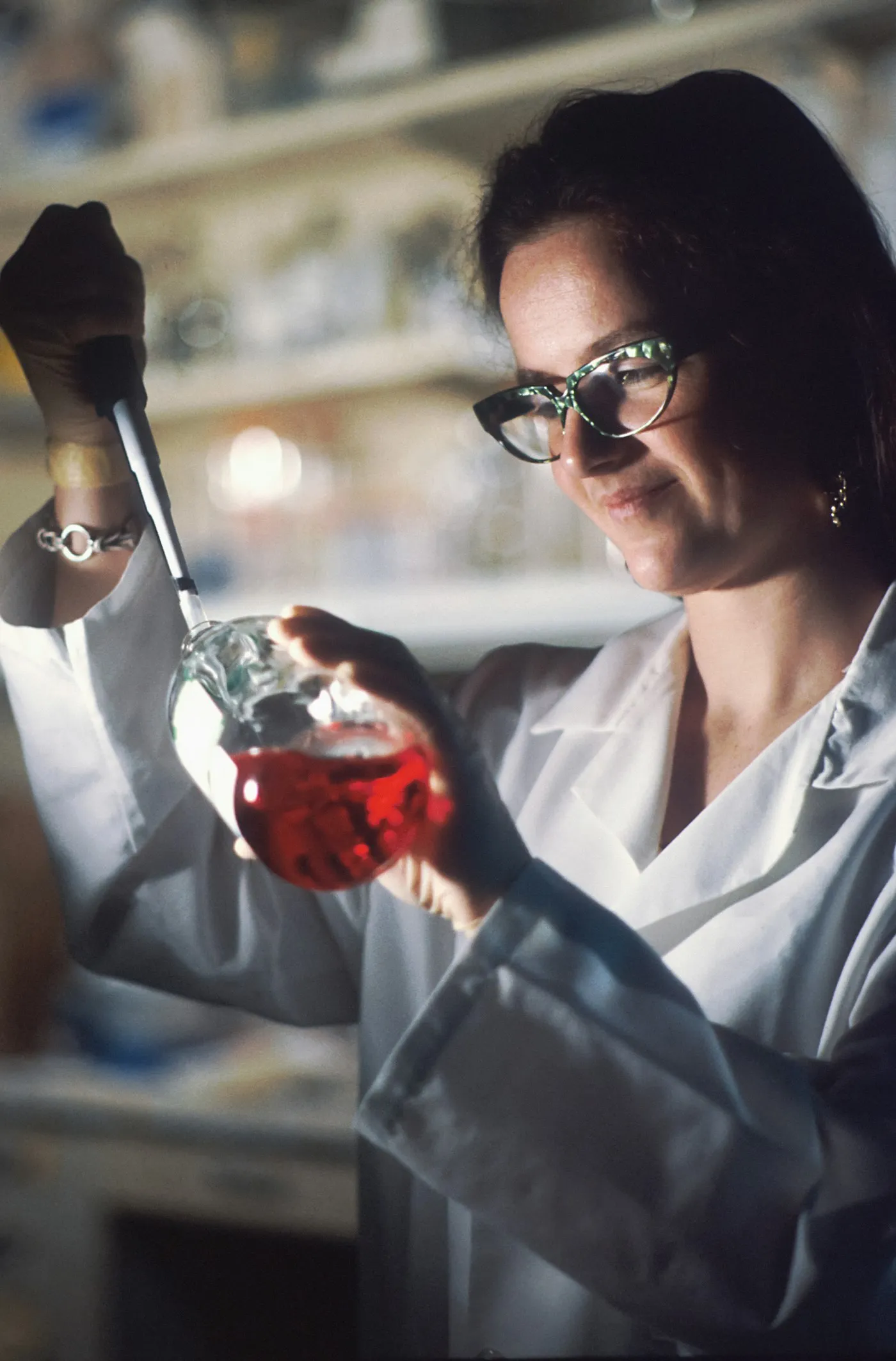 A woman in a lab coat holding a flask of liquid