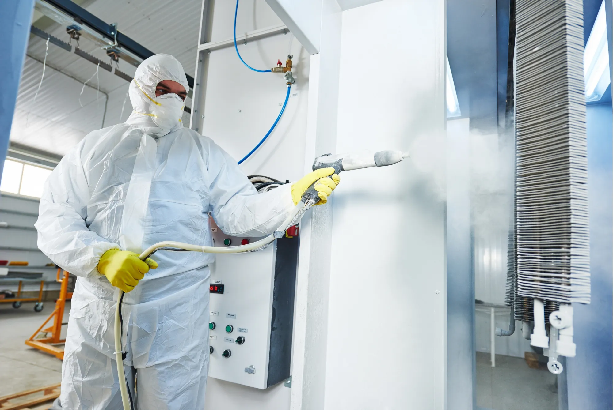 Technician in a protective suit disinfecting a room