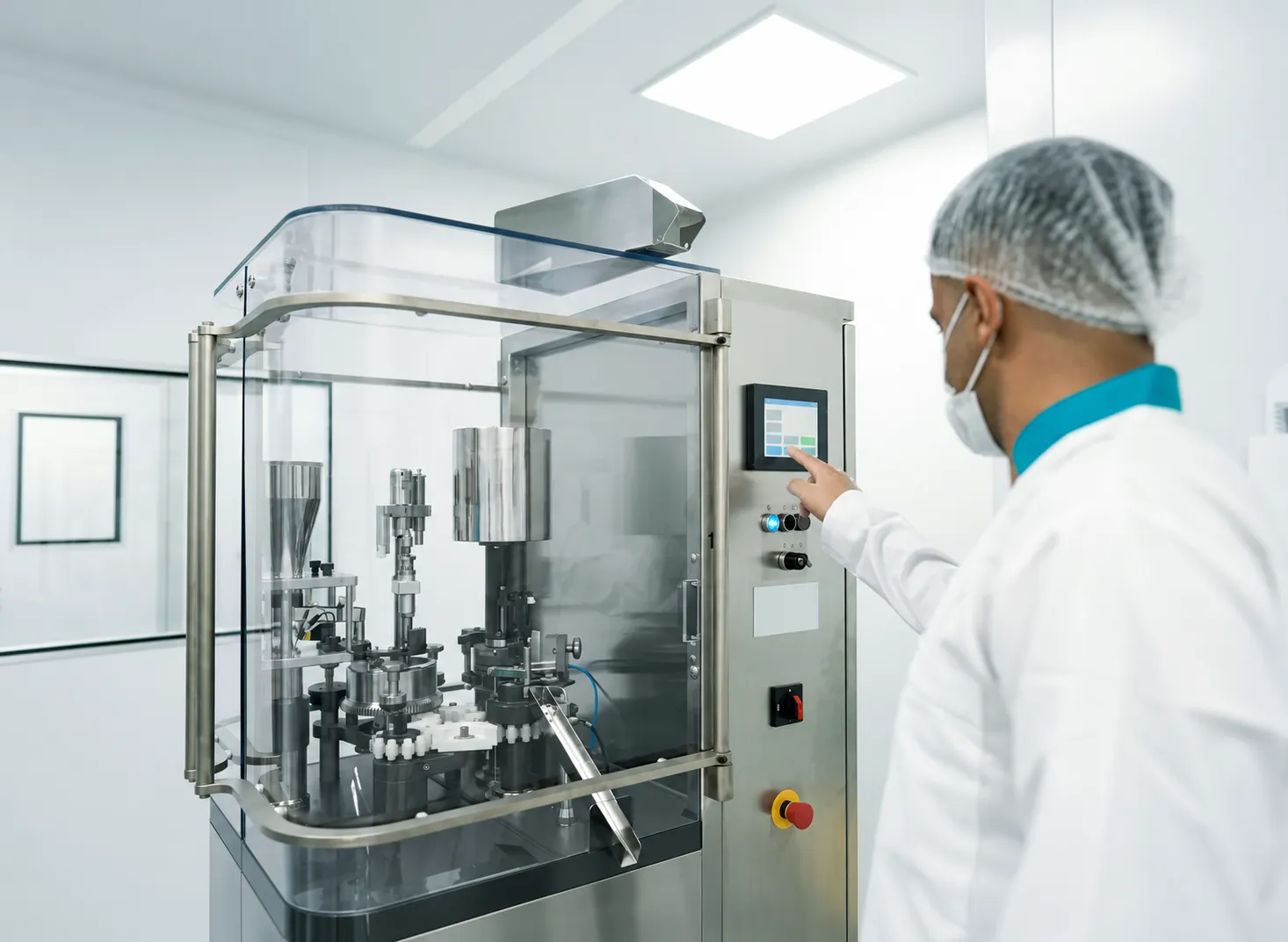 Opérateur en salle propre devant une machine de production stérile